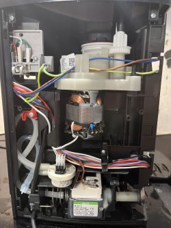 Wnętrze ekspresu do kawy De'Longhi Magnifica z widocznymi elementami elektronicznymi i przewodami.