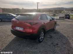 Red Mazda car on a gravel parking lot with visible license plate.