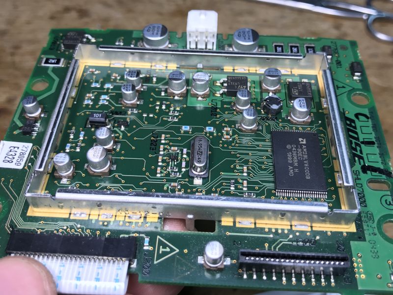 Zbliżenie na wnętrze płytki elektronicznej z komponentami, w tym układy scalone i kondensatory.