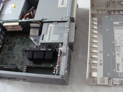 Otwarta obudowa komputera IBM PC 300 z widoczną płytą główną i zasilaczem, obok zdjęta pokrywa.