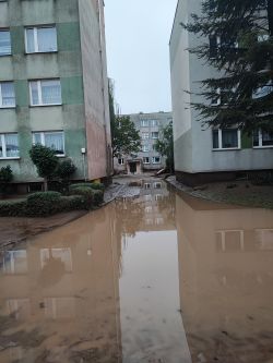 Widok zalanego podwórka między budynkami mieszkalnymi.