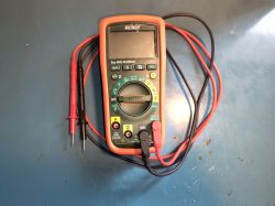 Cyfrowy multimetr Extech EX350 z podłączonymi przewodami pomiarowymi na niebieskim blacie.