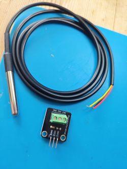 Temperature probe with wiring and a connector board on a blue background.