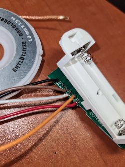 Close-up of an electronic module with connected wires and a battery compartment.