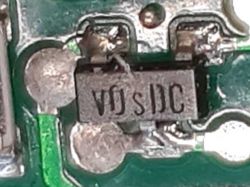 Komponent SMD z oznaczeniem „V0 s DC” na PCB Zbliżenie komponentu SMD z oznaczeniem „V0 s DC” na płytce drukowanej.