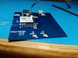 Close-up of a blue PCB with an electronic module and connected wires.