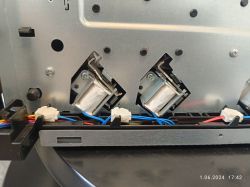 Widok wnętrza urządzenia elektronicznego z widocznymi przewodami i elementami montażowymi.