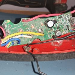 Zdjęcie płytki elektronicznej w urządzeniu Milwaukee M18 z widocznymi kablami i kondensatorami.