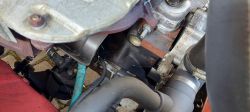 Zbliżenie na silnik samochodu z widocznymi przewodami i elementami mechanicznymi.
