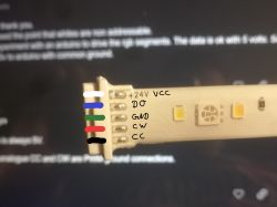 Close-up of an LED strip with pins labeled with colors and descriptions: +24V VCC, D0, GND, CW, CC.