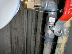 Zawór kulowy z czerwonym uchwytem zainstalowany na rurze, napis CW617N jest widoczny.
