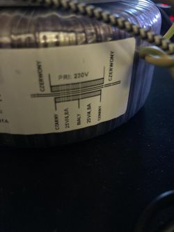 Transformator toroidalny z etykietą połączeniową.