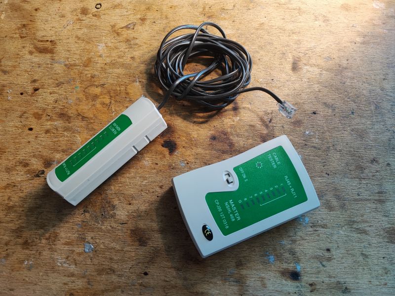 Tester kabli RJ45/RJ11 na drewnianym tle.