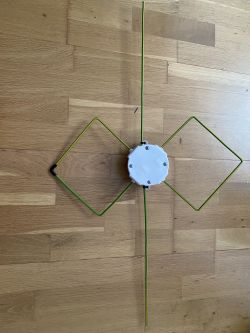 Domowa antena Bi-Quad z dodatkowym dipolem półfalowym umieszczona na drewnianej podłodze.