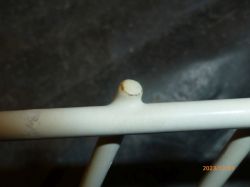 Zbliżenie na metalowy kosz z widocznym ogniskiem rdzy pod farbą proszkową.