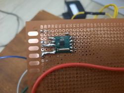 Moduł elektroniczny na płytce prototypowej z podłączonym czerwoną przewodem.