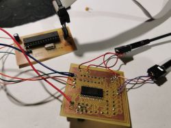 Two PCBs with an IC and multiple wires connected, placed on a white tabletop.