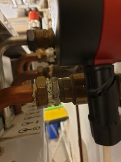 Zbliżenie na elementy instalacji grzewczej z rurami miedzianymi i złączkami.