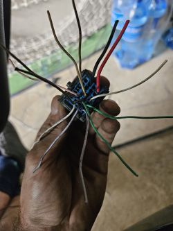 Ręka trzymająca wiązkę kabli z różnokolorowymi przewodami.