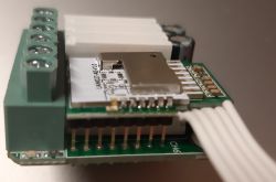 Close-up of an electronic circuit marked UAM027-A0-V1.0 with cable connections.