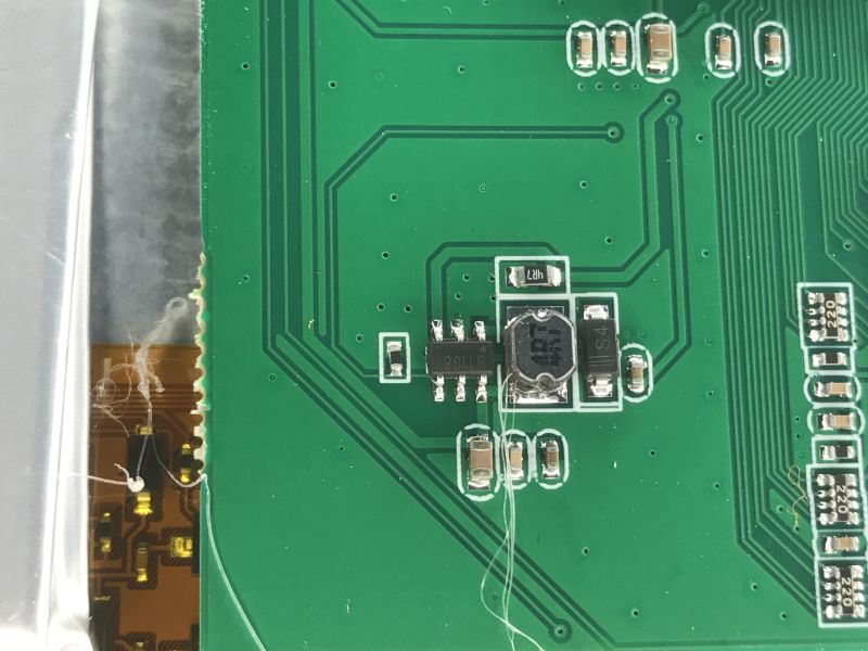 Close-up of a green PCB with SMD parts and a shielded inductor coil
