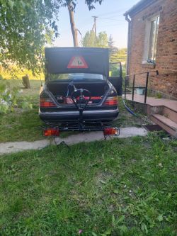 Tył samochodu z otwartym bagażnikiem i przymocowanym hakiem holowniczym, na trawniku przed domem.