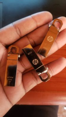 Three metal HP USB flash drives held in a hand.