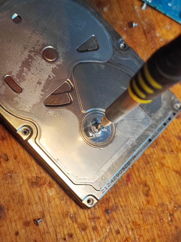 Hard Drive with Moisture and Screwdriver Hard drive with moisture marks and a screwdriver removing a screw