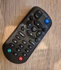 Remote control with numeric and control buttons on a wooden surface