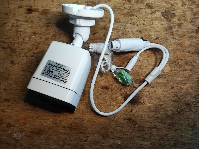 Kamera IP Keview HS400Z6-P oraz akcesoria na drewnianym stole