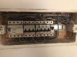 Wnętrze rozdzielnicy elektrycznej z sześcioma wyłącznikami nadmiarowo-prądowymi i przewodami.
