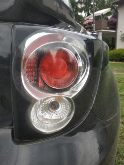 Tylna lampa samochodowa z trzema żarówkami, w tym jedną czerwoną.