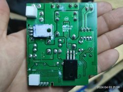 Płytka drukowana trzymana w dłoni z elementami elektronicznymi i oznaczeniami.