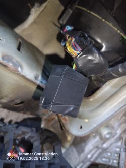 Widok na improwizowaną instalację elektryczną w pojeździe ukazującą złączkę i czarne pudełko.