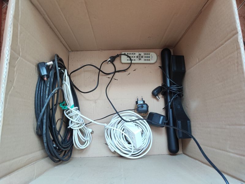 Wnętrze pudełka z pilotem, kablami antenowymi i zasilaczem do telewizora kineskopowego Daewoo K14C5GT.