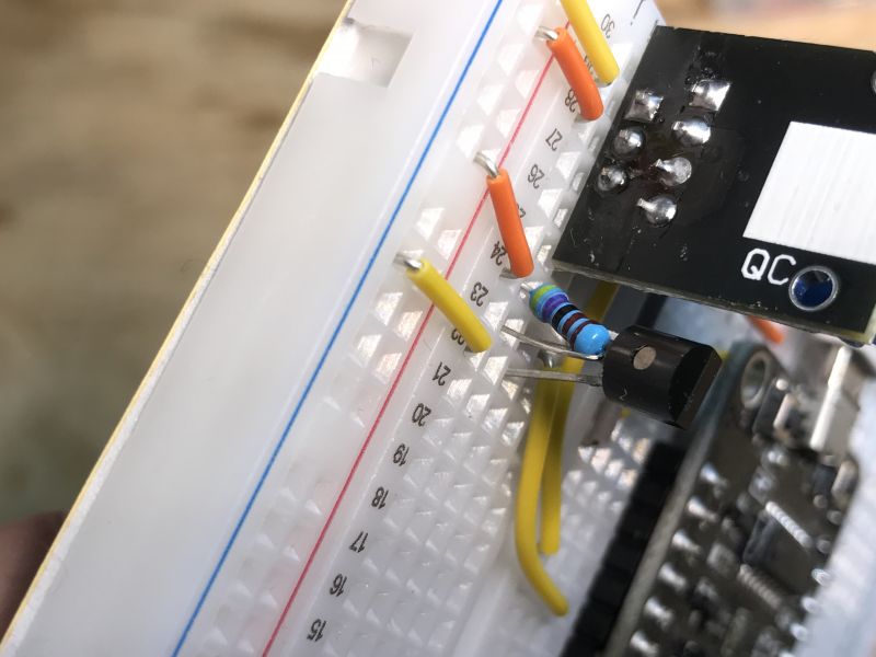 Close-up of a DS18B20 temperature sensor mounted on a breadboard with connected wires and a resistor.