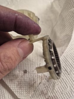Zniszczona zębatka z przekładni wiertarki Parkside PABSP 20 Li C4 Uszkodzona plastikowa zębatka przekładni wiertarki trzymana w brudnych palcach