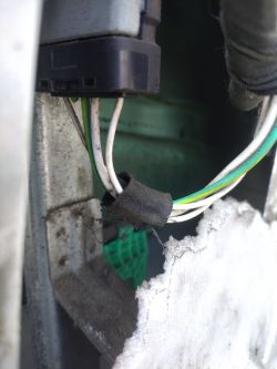 Zbliżenie na wiązkę kabli w drzwiach samochodu z widocznymi kolorowymi przewodami.