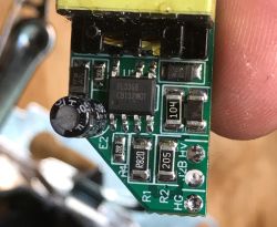 Close-up of a green PCB with PL3368 IC and electrolytic capacitor, held between fingers