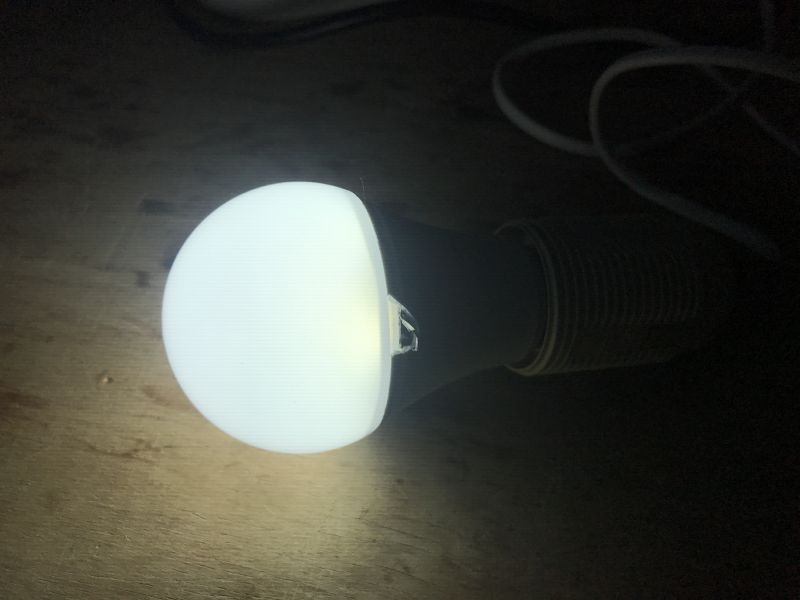 Illuminated TNCE Smart E27 Bulb Illuminated TNCE Smart E27 - TCDPA601WL265 bulb lying on a wooden surface.