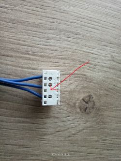 Złącze elektryczne z niebieskimi przewodami na tle drewnianego blatu.