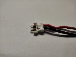 Biały wtyk z dwoma przewodami: czerwonym i czarnym.