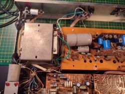 Zdjęcie transformatora i płytki drukowanej w urządzeniu elektronicznym z widocznymi elementami.