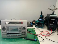 Radio samochodowe i sprzęt lutowniczy na biurku.