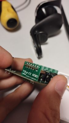 Close-up of a hand holding a circuit board with an attached chip.