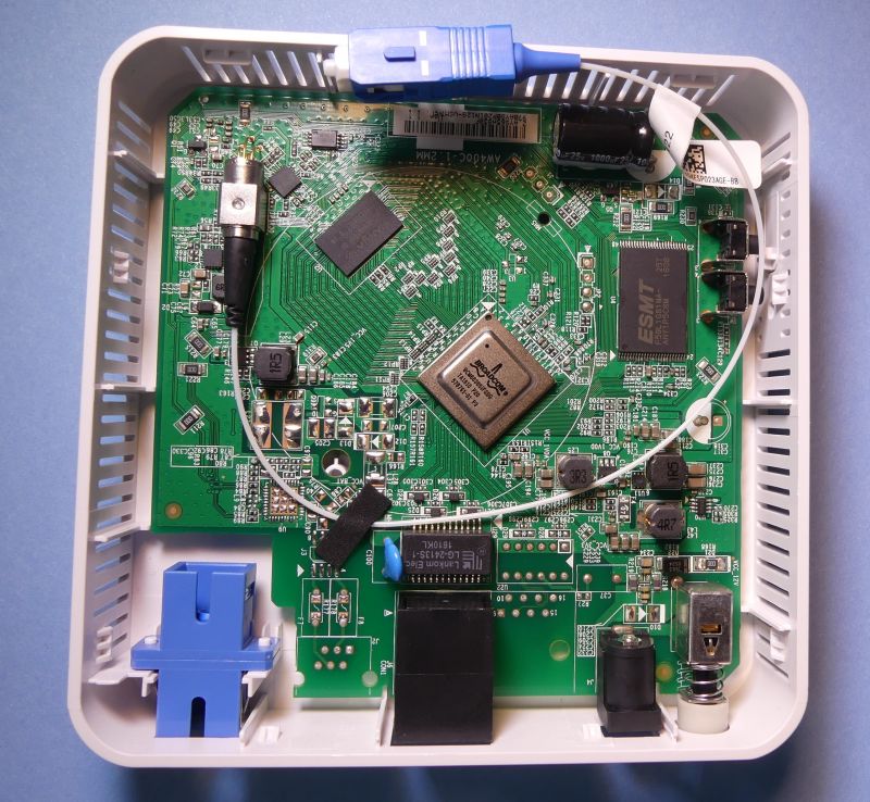 Widok wnętrza urządzenia ONT GPON z widoczną płytą główną, pigtailiem z zakończeniem SC oraz złączami optycznym i RJ45.
