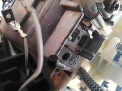 Zbliżenie na wnętrze ekspresu do kawy z widocznymi przewodami i elementami elektrycznymi.