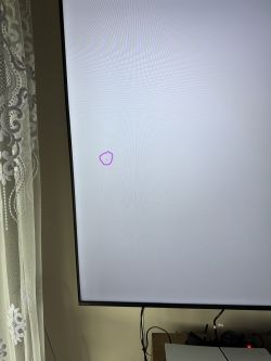 Ekran telewizora z białym tłem i małą ciemną plamką zaznaczoną fioletowym kółkiem