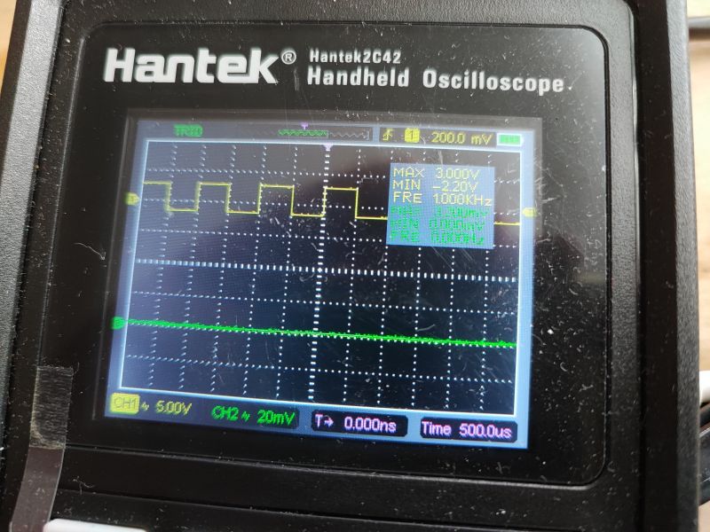 Handheld Hantek Oscilloscope with Signal Waveform Handheld Hantek oscilloscope displaying a signal waveform.