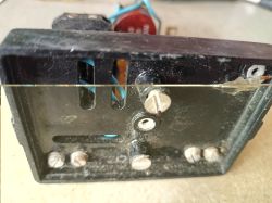 Close-up of a black device housing with vent slots, screws, and internal wires visible.